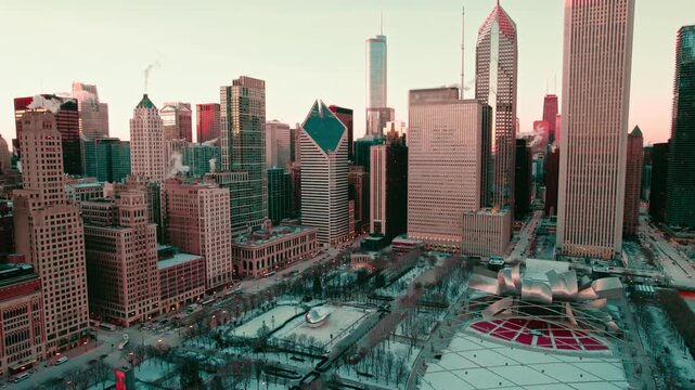 Stunning aerial panorama of downtown chicago cityscape, illinois, with snow covered millennium park during golden hour, majestic skyscrapers under clear sky.