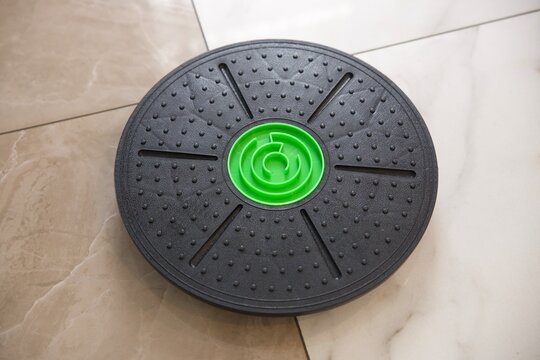 Black circular balance board with textured surface and bright green center for home fitness, balance training, core strengthening and physical therapy. Portable non-slip equipment for stability,