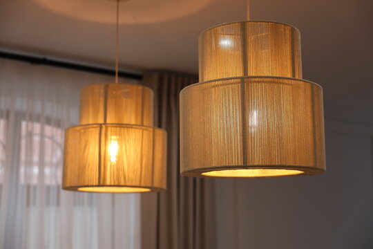 Warm pendant lamps cast a soft ambient glow over a modern living room with sheer curtains, creating a cozy, elegant interior atmosphere ideal for evening relaxation and stylish home decor inspiration.