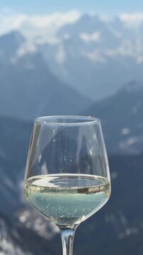 Glass of Prosecco with panoramic views of the Dolomites in the Dolomiti Superski region, Italy. Alpine lifestyle, slow living and mountain relaxation surrounded by snowy peaks