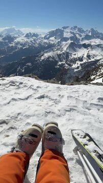 POV of a skier resting at a panoramic viewpoint near Cortina d'Ampezzo. Snow-covered Dolomite peaks, alpine scenery and the relaxed spirit of Dolomiti Superski and mountain living