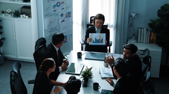 Top view of smart business woman show increasing sales chart to diverse team while group of diverse business people listening and analyzing stock investment data at table with document. Directorate.