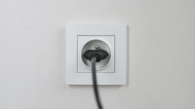 Closeup Hand Plugging Charger Into White Power Socket