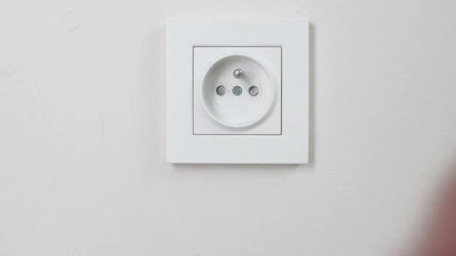 Closeup Male Hand Unplugging Charger From Wall Socket