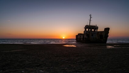 Obraz premium Warm sunset illuminating a shipwreck on a quiet oceanfront