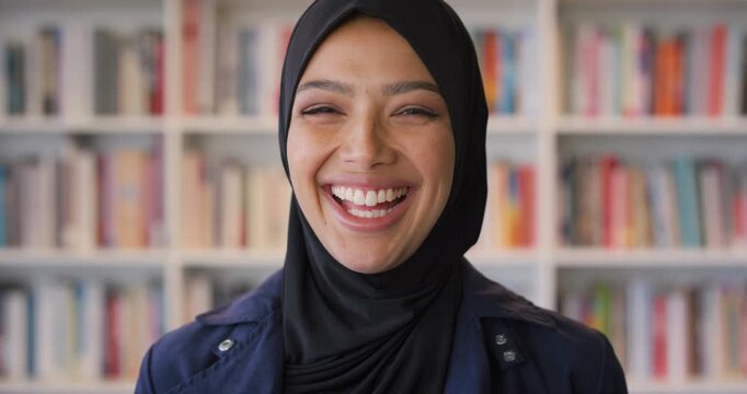 Smile, laugh and face of muslim woman in library for university, education or studying with knowledge. Hijab, portrait and islamic student in college with humor, funny joke and campus scholarship
