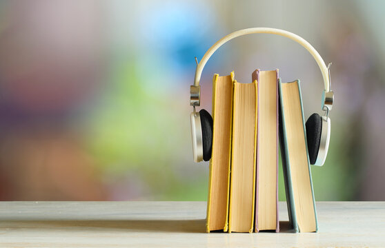 audiobooks concept with  stack of books and headphones, smooth blurry background.