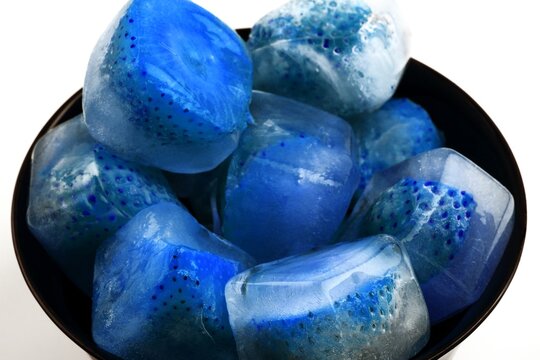 Frozen strawberries in ice cubes with melting water and reflections