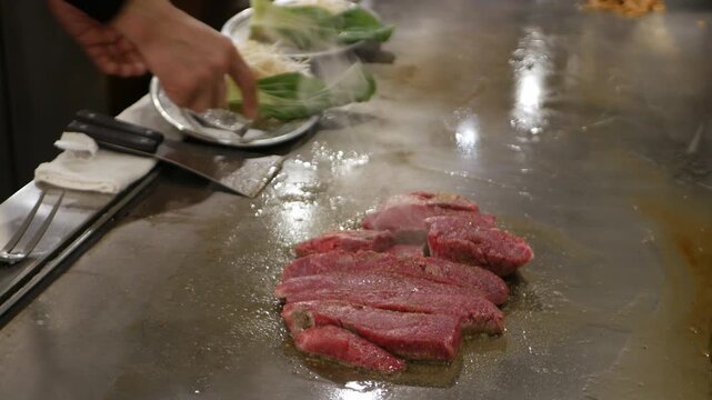 POV to kobe sirloin wagyu steak while cooking on teppan yaki flat pan in japanese style restaurant for lunch time. Chef cooking wagyu kobe beef sirloin steak on teppanyaki flat pan