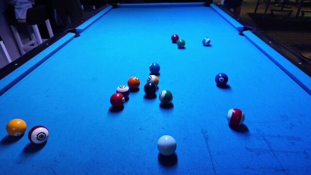 Woman breaking racked pool balls in eight-ball on billiard table
