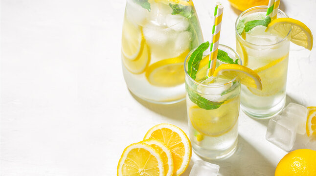 Fresh homemade lemonade with lemon slices, mint and ice on white background, summer drink concept