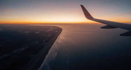 Obraz premium Serene aerial sunset over ocean with sandy coast and airplane wing