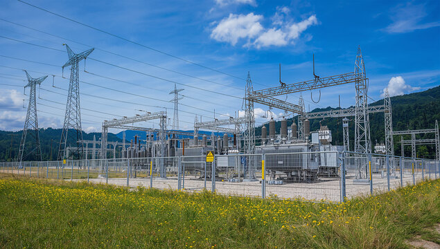 山のふもとの変電所で電力設備と送電線が並ぶインフラ風景