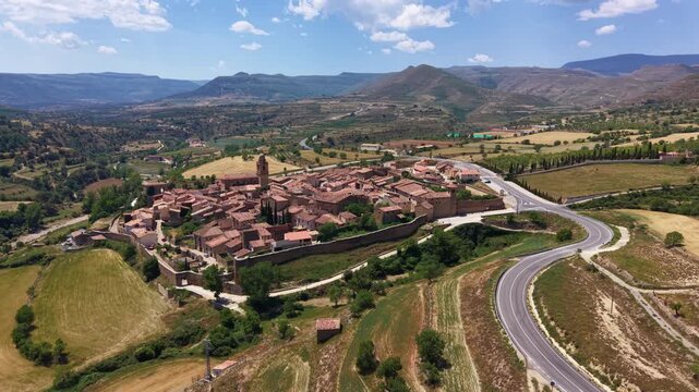 Panoramic aerial view of Mirambel, a 13th-century walled medieval village in Maestrazgo, Teruel, Aragon, Spain, with stone houses, terracotta rooftops, church bell tower and mountain valley