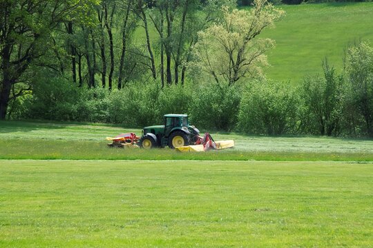 Liezen, Austria 05 10 2026:  farmer on a tractor is mowing a field of grass in the Austria region of Styria