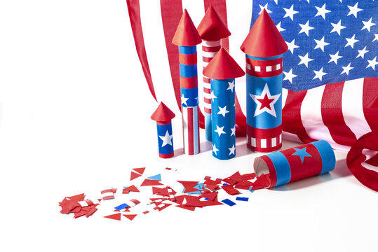 Fourth of July USA Independence Day festive celebration concept with copy space. Handmade craft paper rockets decorated with stars and stripes, USA flag, white background.