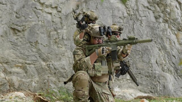 Special forces soldiers in full tactical gear on a military mission, securing a rocky perimeter while aiming their assault rifles in a coordinated team operation.