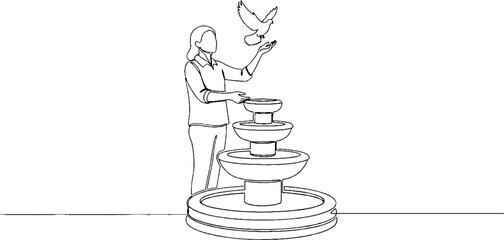 Fototapeta premium Woman interacting with bird at tiered fountain.