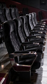 Generative AI depicts a row of plush black theater chairs in an elegant auditorium