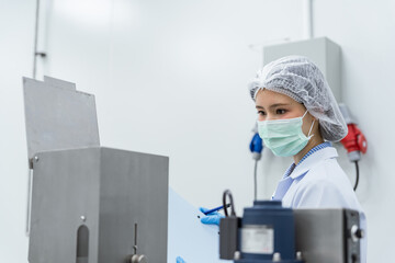 Naklejka premium Young scientist in protective gear operating machinery. Quality control inspector and factory workers operating automated packaging machinery in a sterile pharmaceutical manufacturing facility.