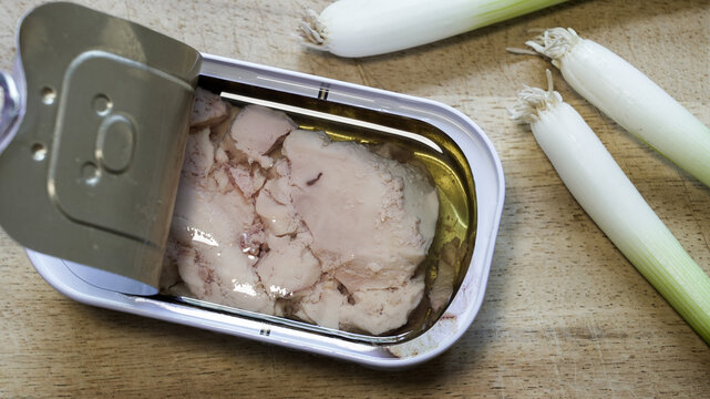 Open can of seafood cod liver on wooden board