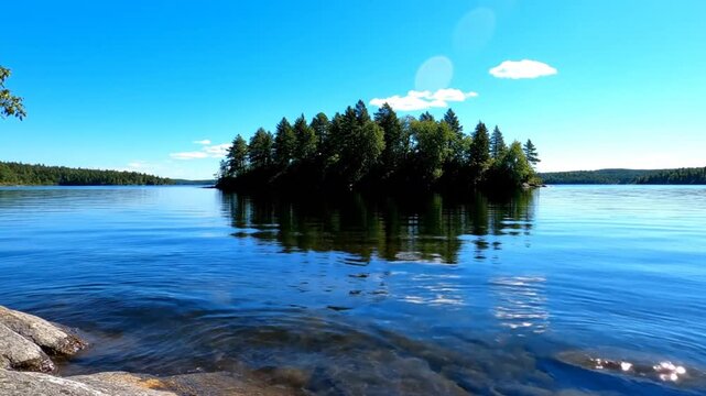 Serene lakeside view with small forested island and blue sky in the summer sun