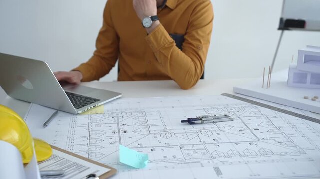 Architect or engineer working on architectural blueprints, drawing construction plans, designing a building project, and planning future development in an office