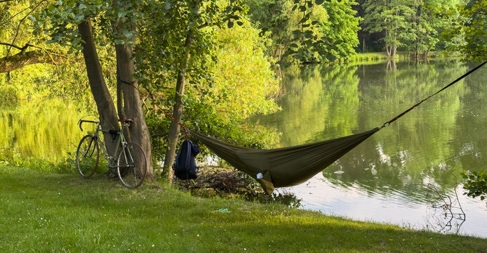 Panorama Hammock by a pond with bicycle and backpack for relaxation in nature