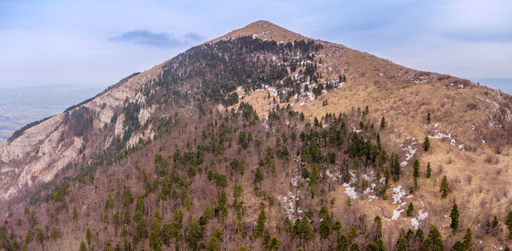 Rtanj mountain in Serbia featuring its distinctive pyramid shape under a blue sky with scattered clouds, showcasing natural landscape and hiking trails