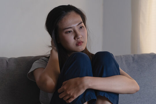 Asian woman covering her face feeling sorrow and depressed sit in the dark bedroom