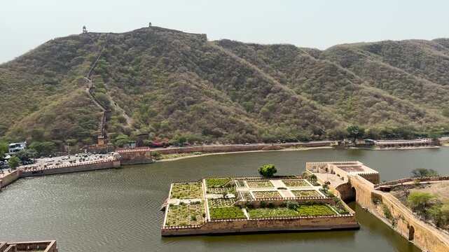 Full lake view of Amer Fort with Maota Lake in the foreground, surrounded by the Aravalli Hills and beautiful garden scenery in Jaipur, Rajasthan, India.
