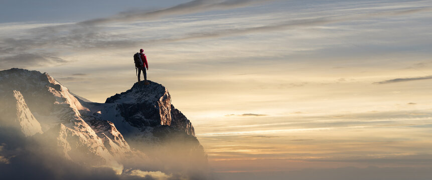 Wanderer auf einem Bergipfel schaut in den Sonnenuntergang