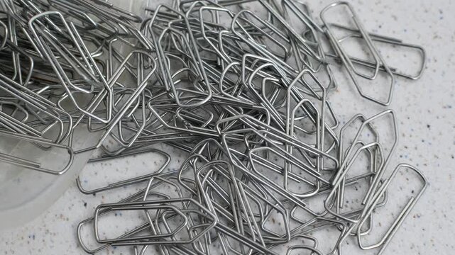 Paper clips intertwined in chaos on a bright surface, a visual representation of disordered creativity.