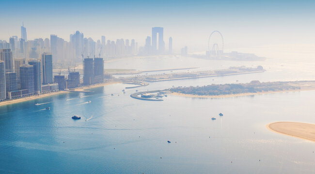 Dubai Marina skyscrapers along the coastline, with the blue waters of the Arabian Gulf and ferris wheel in the distance