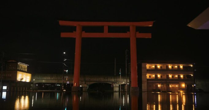 Shimmering artificial pond under massive Japanese torii gate at night