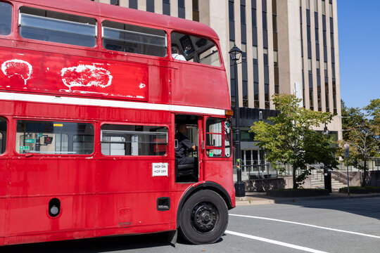 Vintage red double decker sightseeing bus travelling through downtown Halifax Nova Scotia Canada with urban office buildings and city street scene on a sunny day