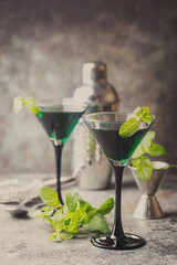 Closeup of green cocktails in martini glasses with mint leaves over gray background © petrrgoskov