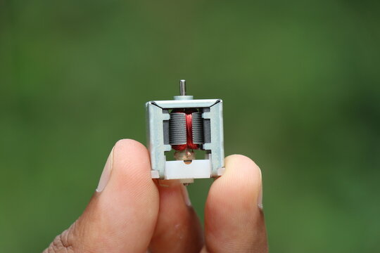 Small DC electric motor with visible copper coil and windings close Up. Open frame DC motor for hobby electronic projects