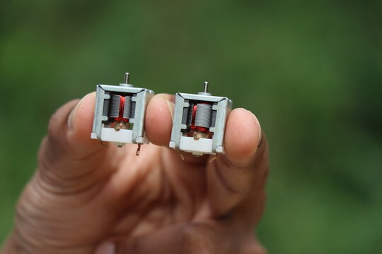 Micro DC motor or known as open frame dc motors held Between fingers with visible copper windings