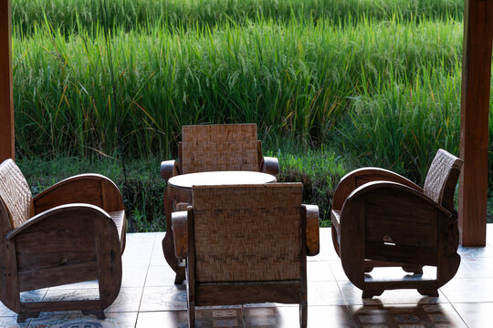 Javanese wooden furniture on patio looking out at green rice field