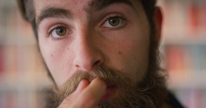 Man, face and confidence with moustache in library for higher education, knowledge and academic books. Student, facial hair and portrait on university campus for scholarship, literature and academy