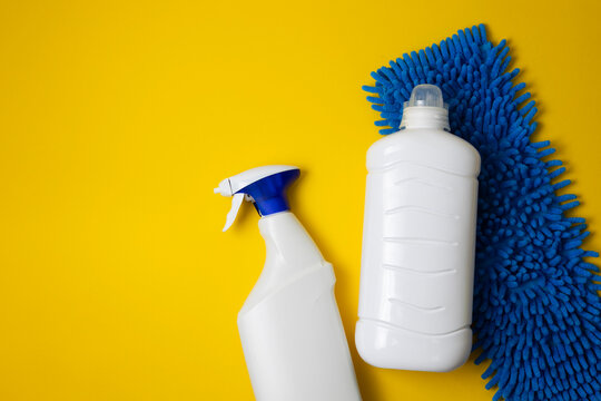 Floor cleaner bottle and microfiber mop on color background