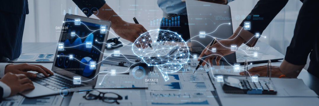 This image captures a business meeting with professionals collaborating over laptops and data charts, featuring a digital brain graphic symbolizing innovative technology and analysis. Trope