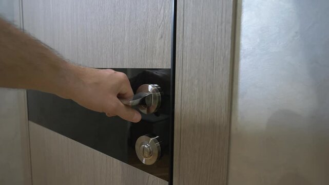 A man tries to open a door in a room that is locked. He pulls the doorknob.