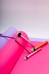Vibrant color papers and makeup brushes create an artful scene in a studio setting at daytime © ir1ska