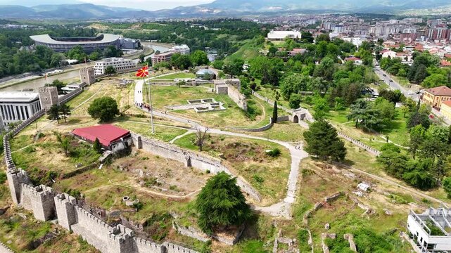 Aerial drone view of Tsar Samuel's Fortress on a hill in Ohrid, North Macedonia, with the national flag waving in the wind. Scenic panorama overlooking Lake Ohrid and the surrounding landscape.	