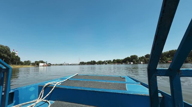 View from a ferry crossing the Sava River between New Belgrade and Ada Ciganlija on a sunny day. Urban transport and recreation concept featuring water travel and local tourism