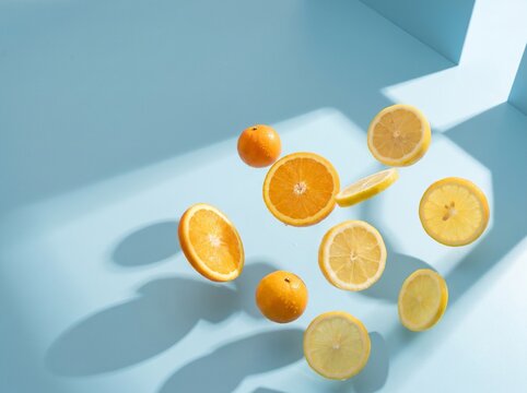 Fresh orange and lemon slices suspended in midair on a light blue