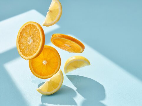 Sliced oranges and lemons floating in midair on blue background