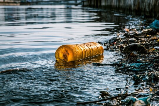 Pollution in river shows discarded items floating on the surface and garbage along the banks during midday sunlight